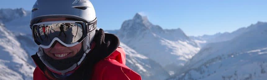 Woman wearing googles with a helmet on top of a snowy mountain